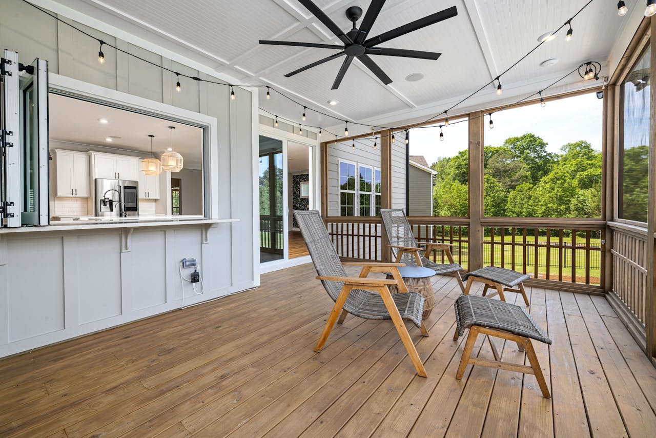 our-stories Inviting porch with modern design featuring wooden chairs, ceiling fan, and scenic view.