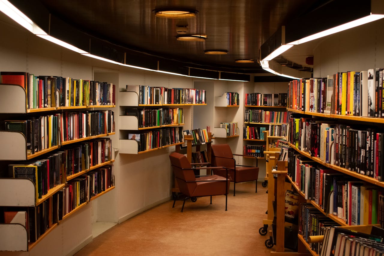 service-05 A cozy library space in Stockholm with brown leather chairs and wooden bookshelves filled with books.