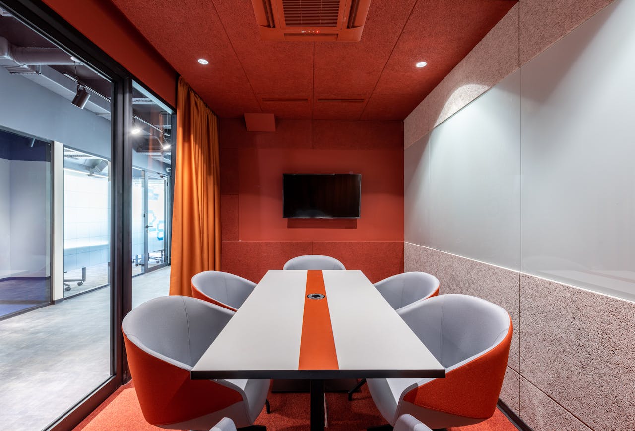 service-01 Stylish modern meeting room with orange accents, glass wall, and contemporary furnishings.
